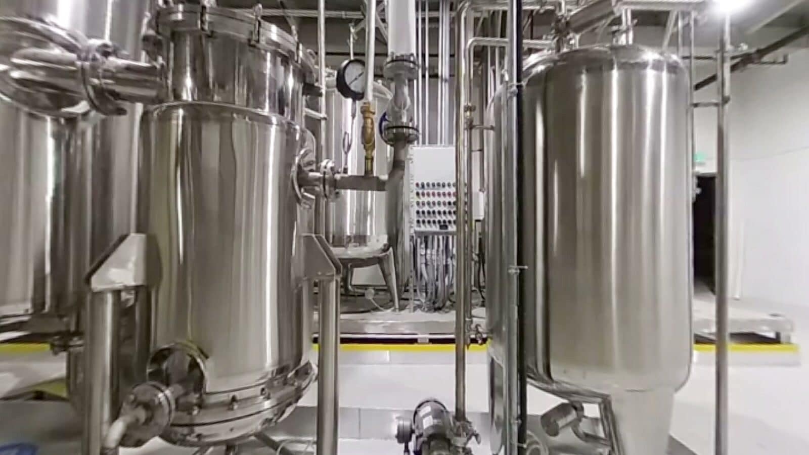 Jacketed stainless vessels and a control cabinet in a white process room