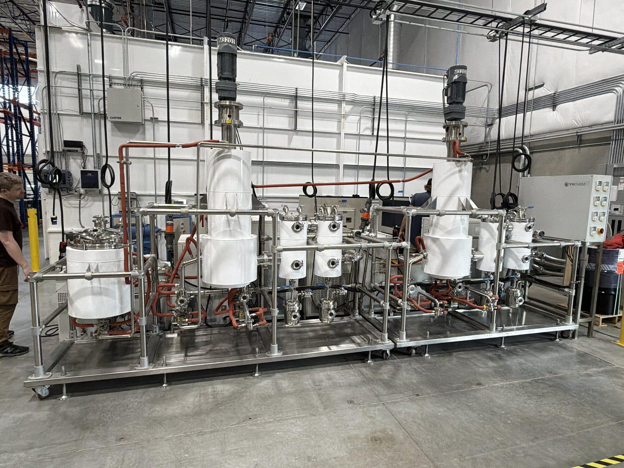 A line of jacketed stainless reactors with heating hoses on a stainless frame, Loveland