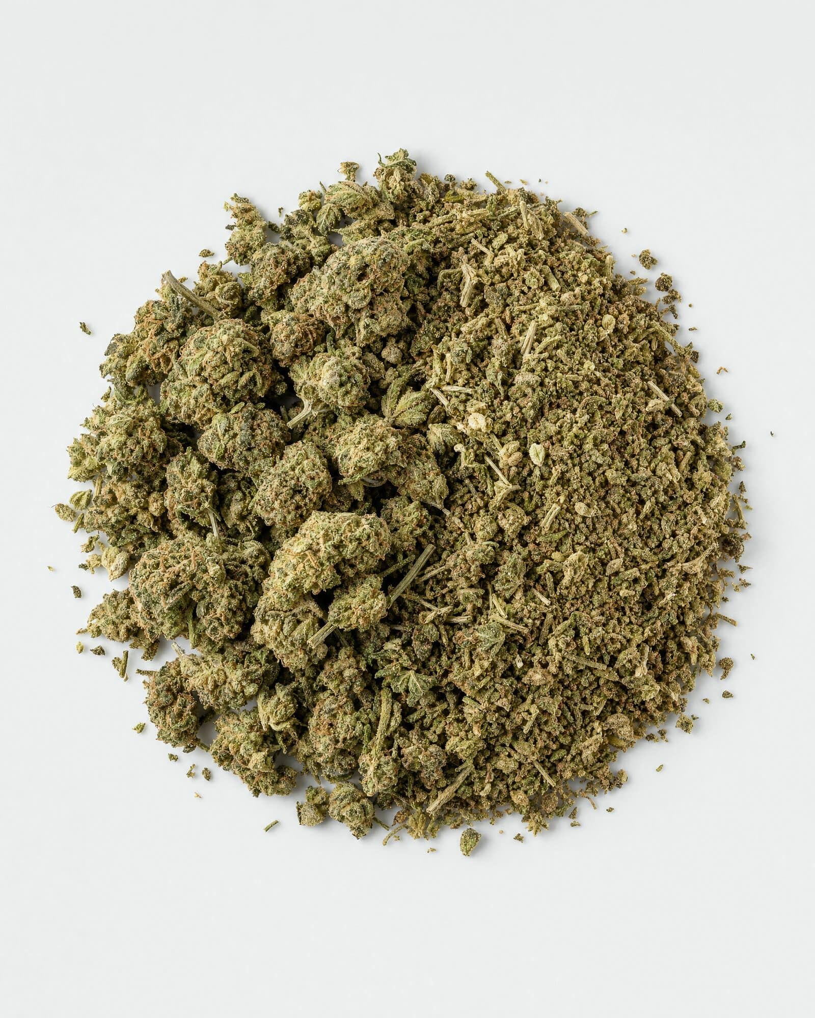 Dried hemp flower and milled hemp biomass in a mound on a white surface