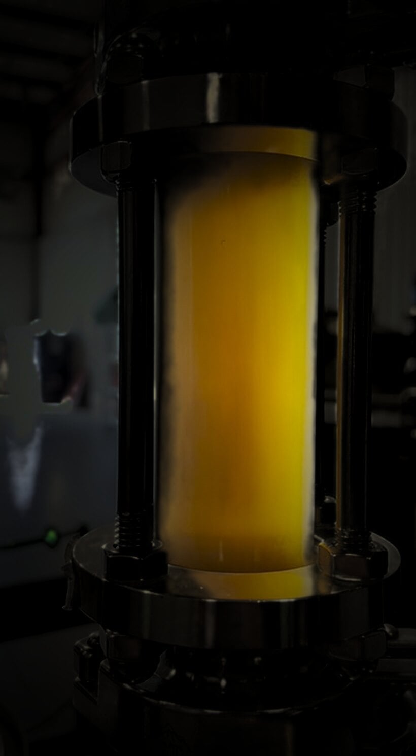 Amber crude filling a sight glass between stainless flanges