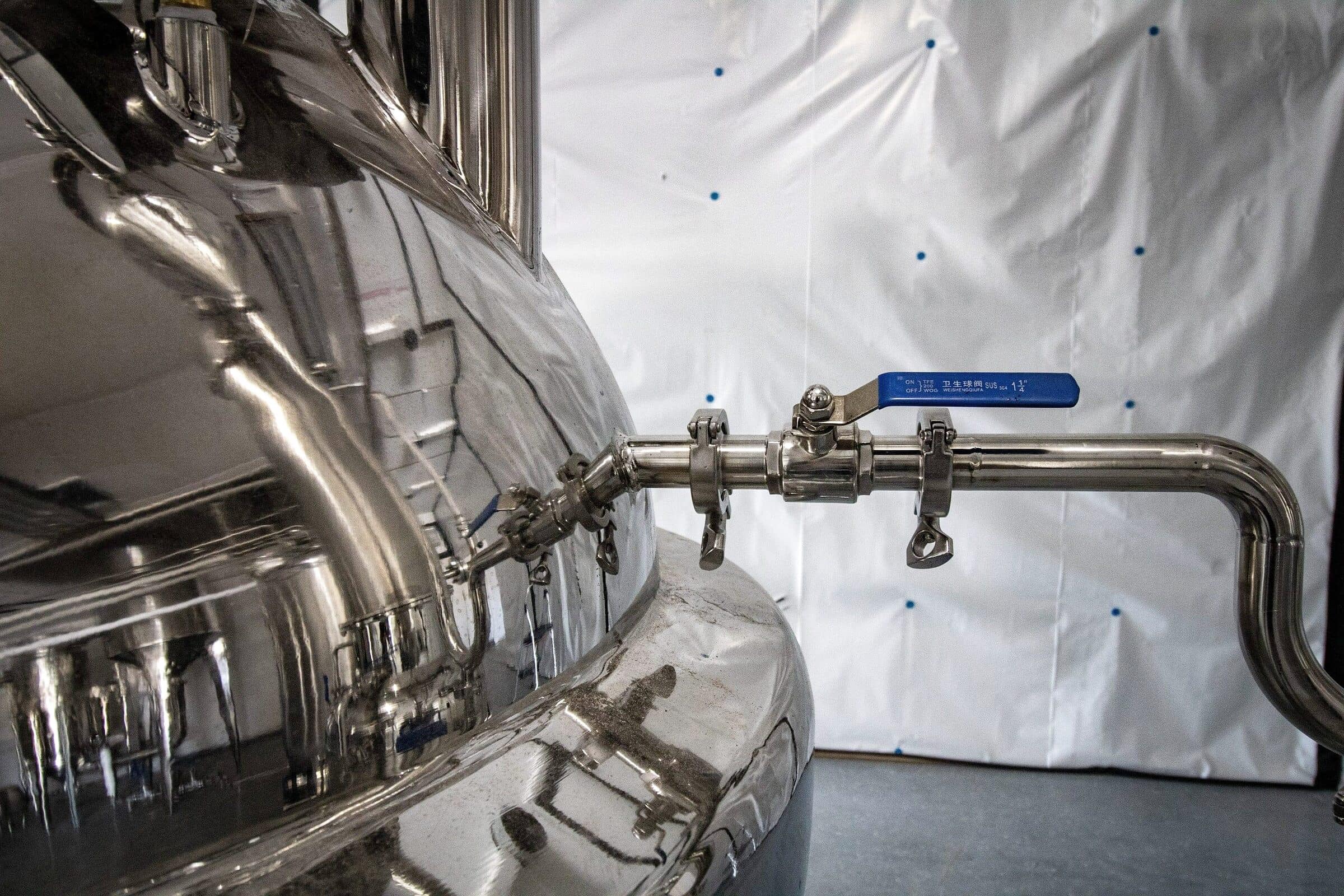 Polished stainless vessel with tri-clamp piping and a sanitary ball valve