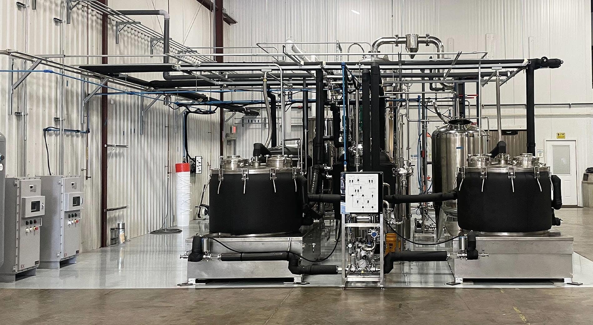 Two insulated extraction vessels either side of a control skid with a white mimic panel